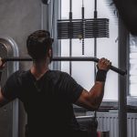Back view of a man exercising with lat pulldown machine in the gym.